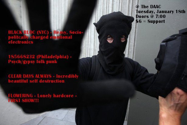 Masked person wearing all black holds their gloved hand up, obscuring the camera