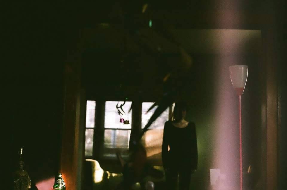 Shadowy photograph of a person standing on the other side of a doorway