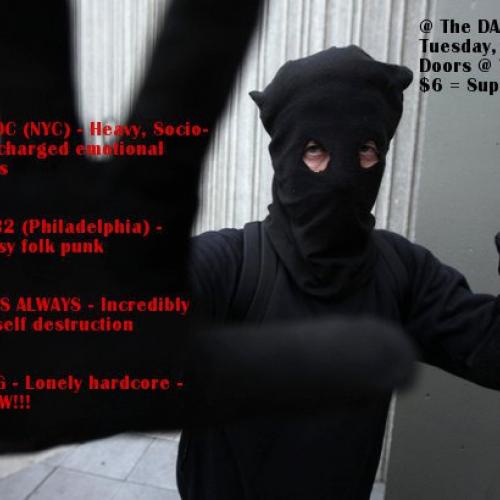 Masked person wearing all black holds their gloved hand up, obscuring the camera