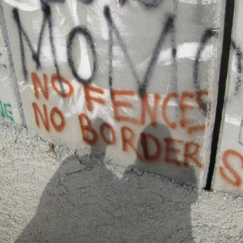 Spray paint on a concrete wall: No Fences No Borders