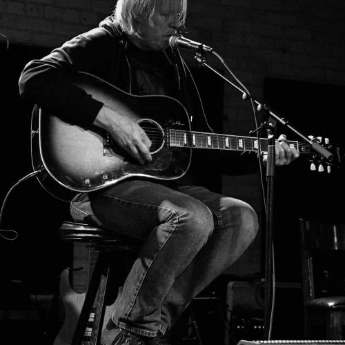 A solo guitarist sings at The DAAC open mic